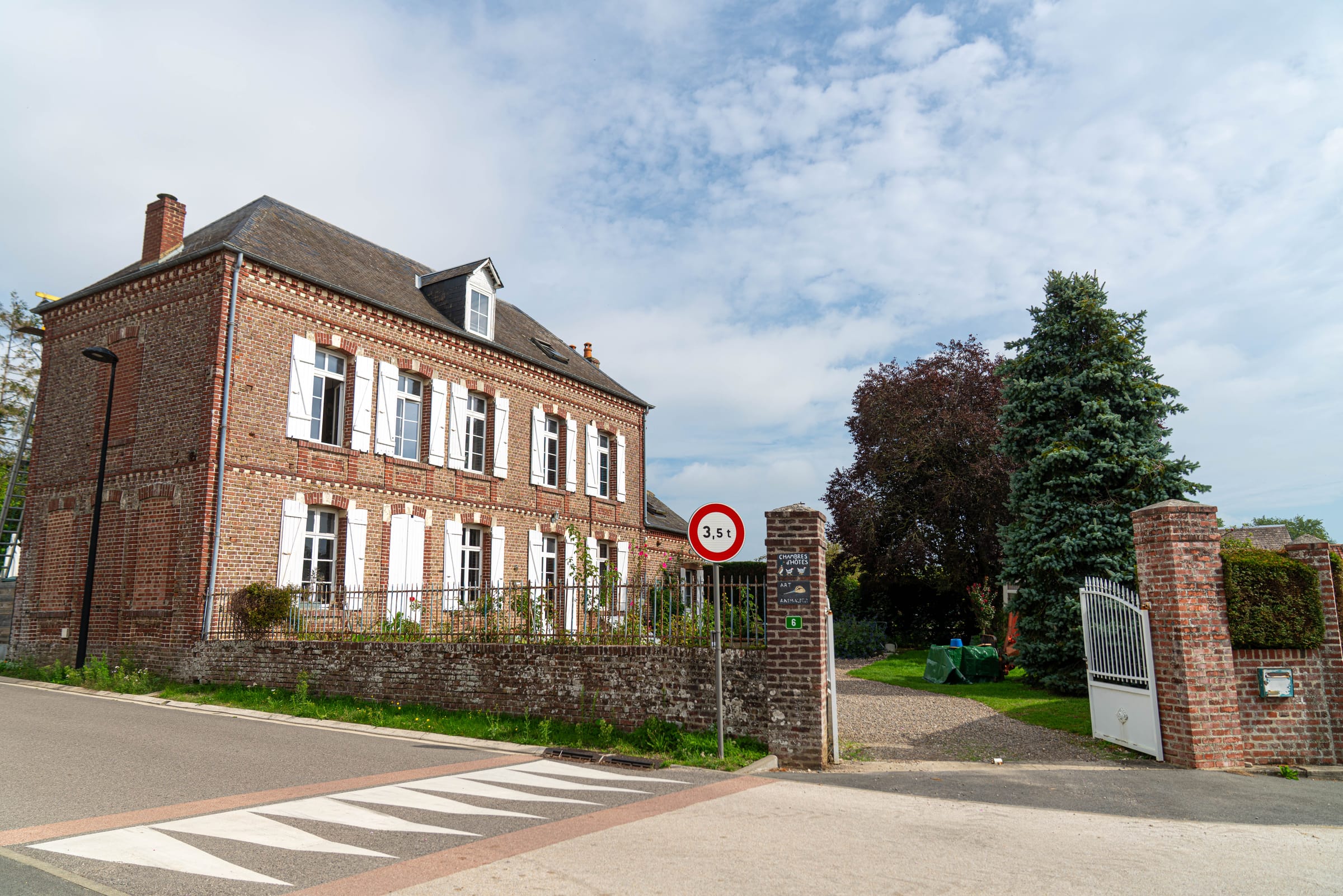 La maison en brique de Chez Agnès et Nicolas, vue depuis la rue sous un ciel nuageux